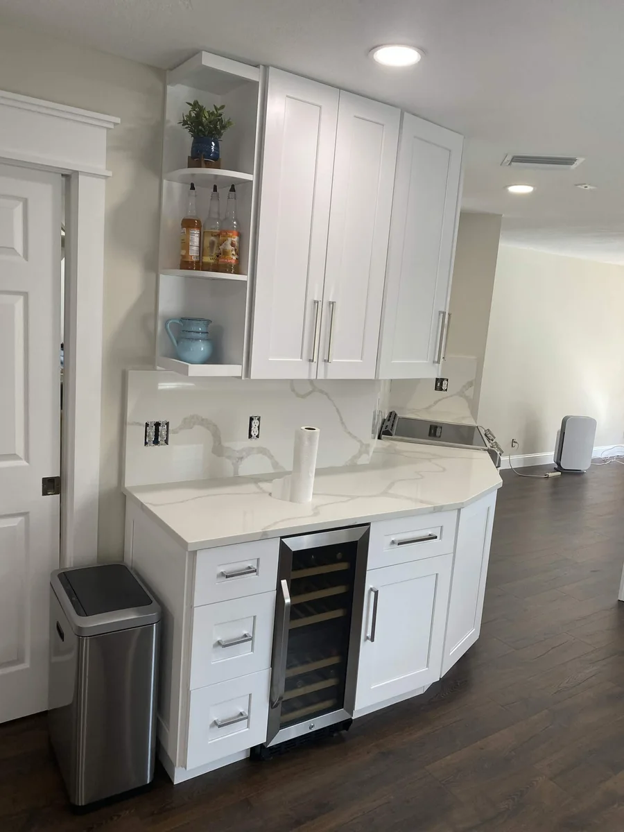 White cabinetry and countertops with a small beverage refrigerator
