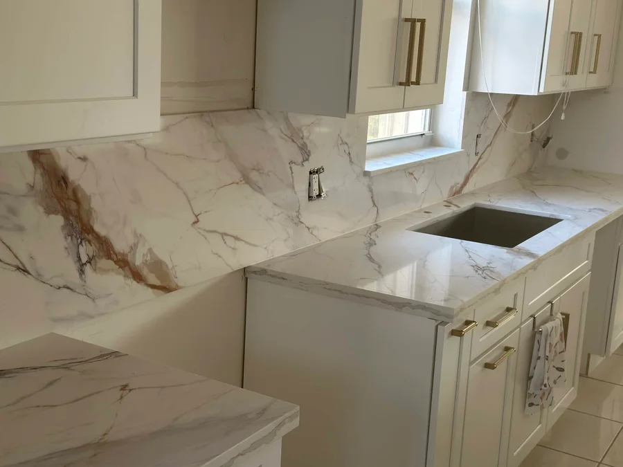 White cabinets with light veined countertops and a backsplash