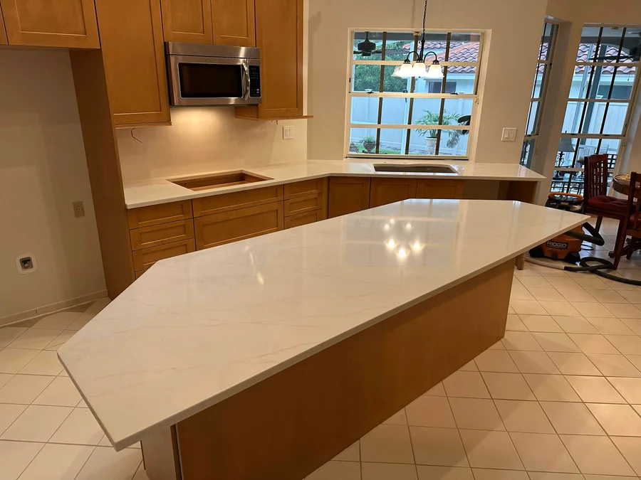 Warm wood kitchen cabinetry with light countertops and an island